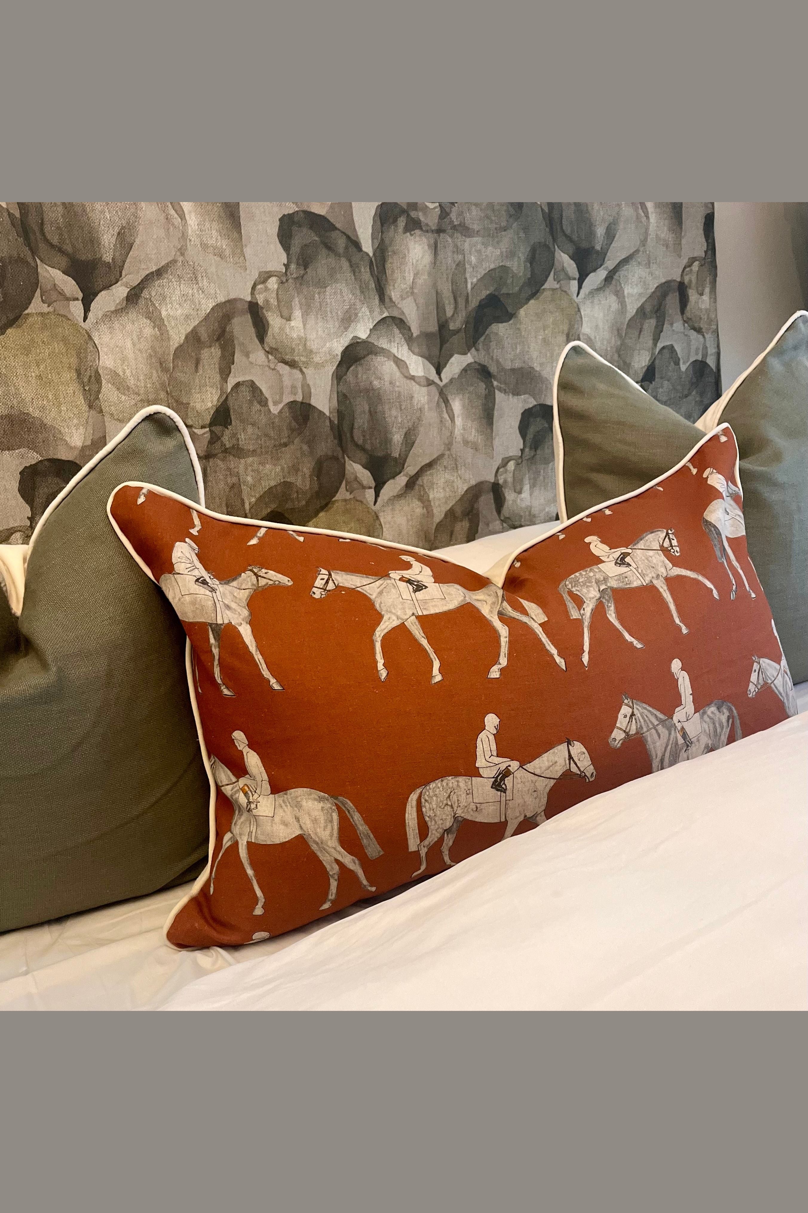 Decorative pillow with horse and rider pattern on a bed with a textured wall in the background