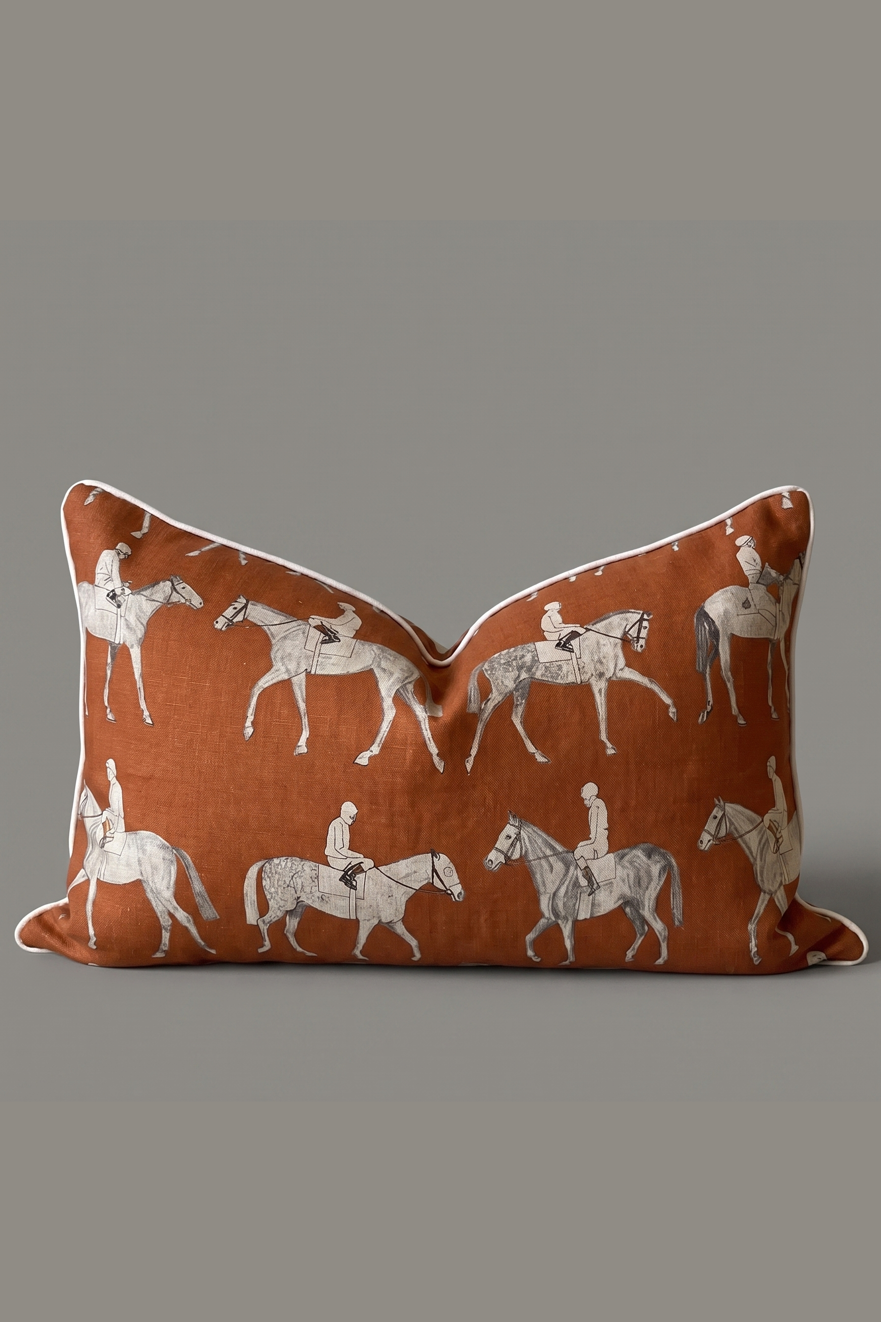 Decorative pillow with horse and rider pattern on a burnt orange background